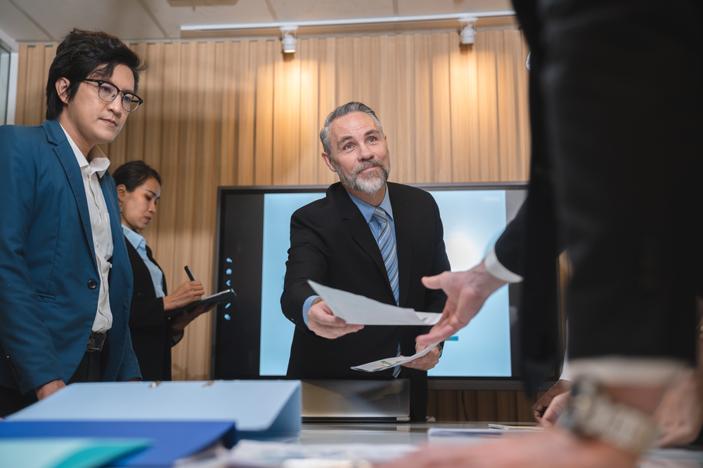 Professional team of focused business executives analyzing company annual financial paper report to balance together at office. Business market with modern office and tax document concept